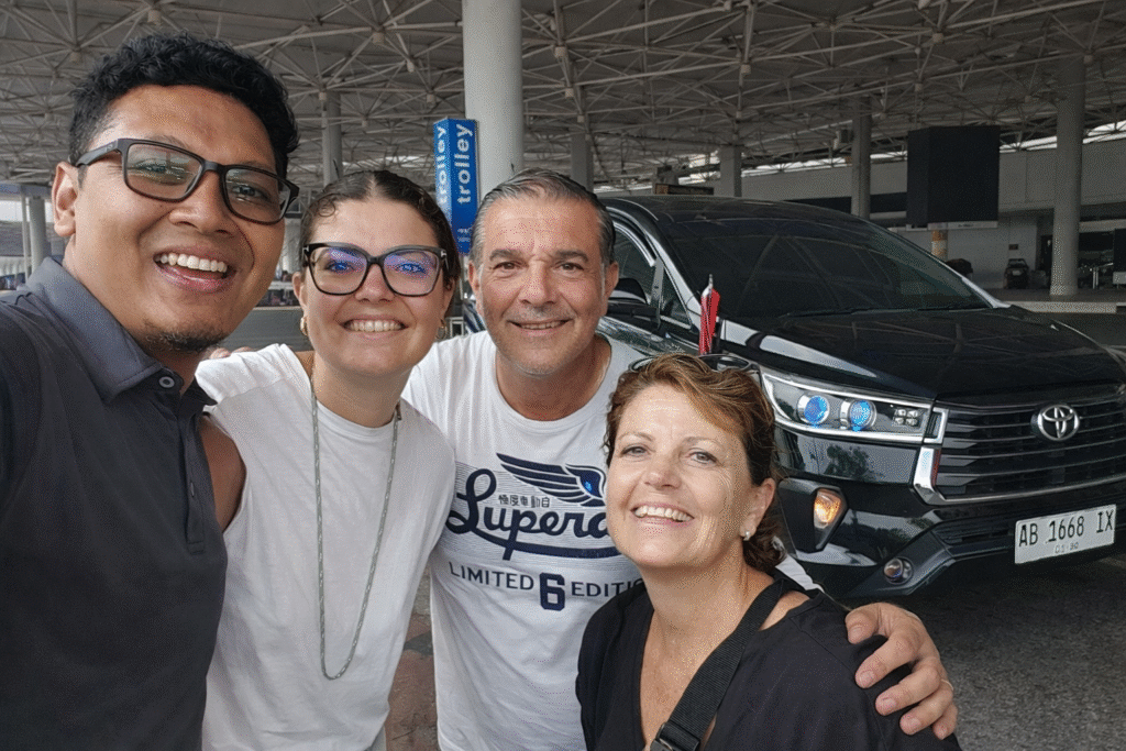 "Zelfportret van vier personen voor een zwarte Toyota met tevreden klanten die een glimlachende tourchauffeur omringen in een luchthaventerminal."