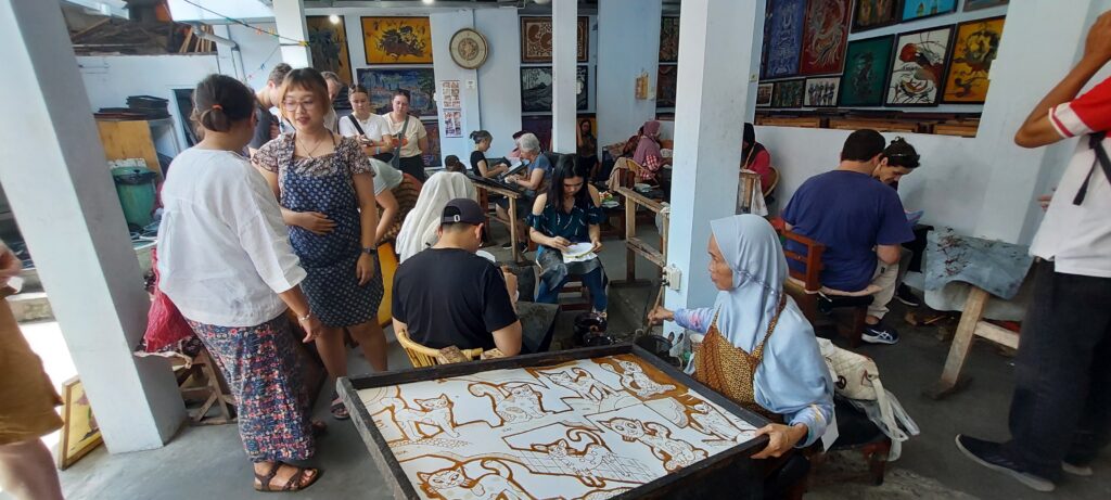 Toeristen leren batik maken met een canting in Jogja