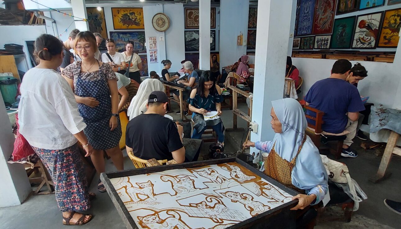 Toeristen leren batik maken met een canting in Jogja