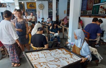 Toeristen leren batik maken met een canting in Jogja