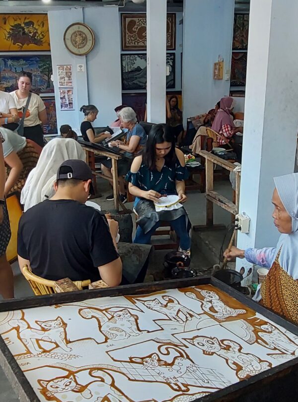 Toeristen leren batik maken met een canting in Jogja
