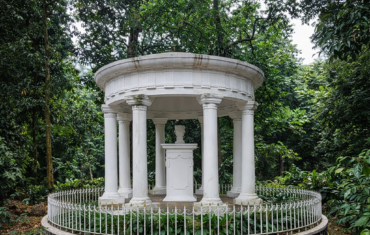 Monument Lady Raffles, een witte ronde rotunda met zuilen in een groen park omringd door bomen.