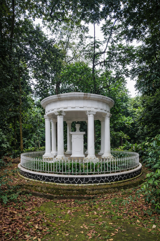 Monument Lady Raffles, witte ronde rotunda met klassieke zuilen in een groen park vol bomen.